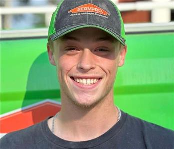 Male SERVPRO employee with black shirt and wearing ballcap